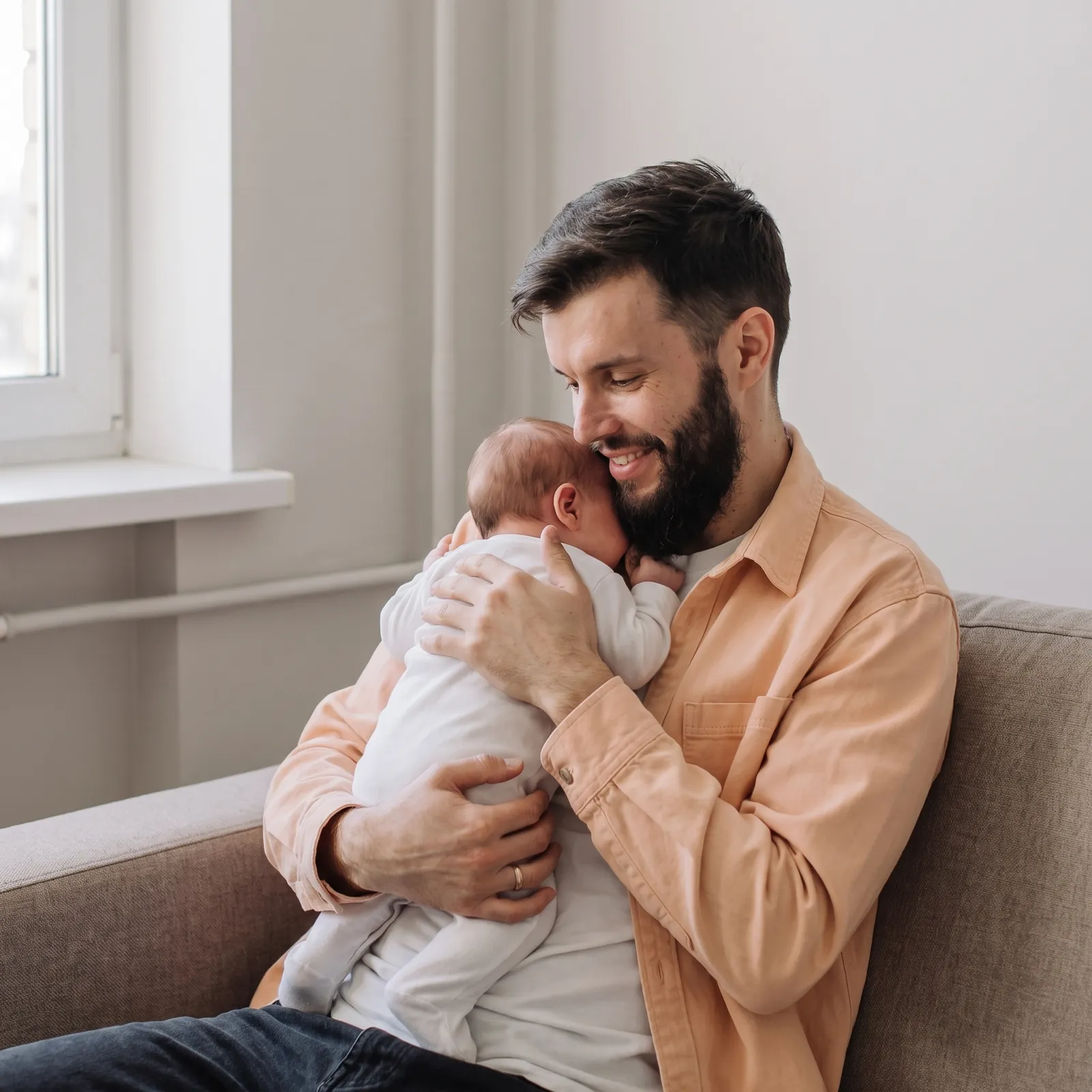 Vader op de bank met zijn baby tegen zijn schouder