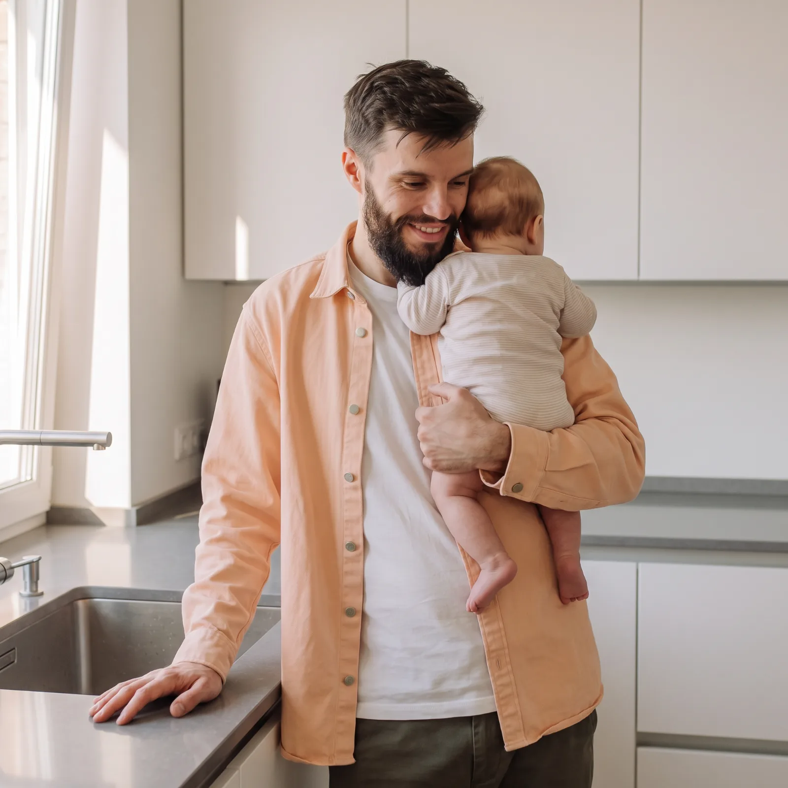 Vader met zijn baby op de arm in de keuken